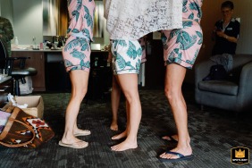 In a Cleveland, Ohio, hotel, a wedding photographer captures a tight detail shot. The image shows bridesmaids helping the bride into her dress, highlighting their matching outfits from the waist down.